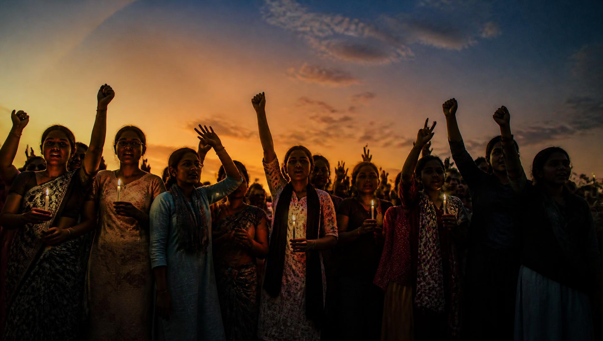 A crowd standing together at dusk holding candles in solidarity against human trafficking